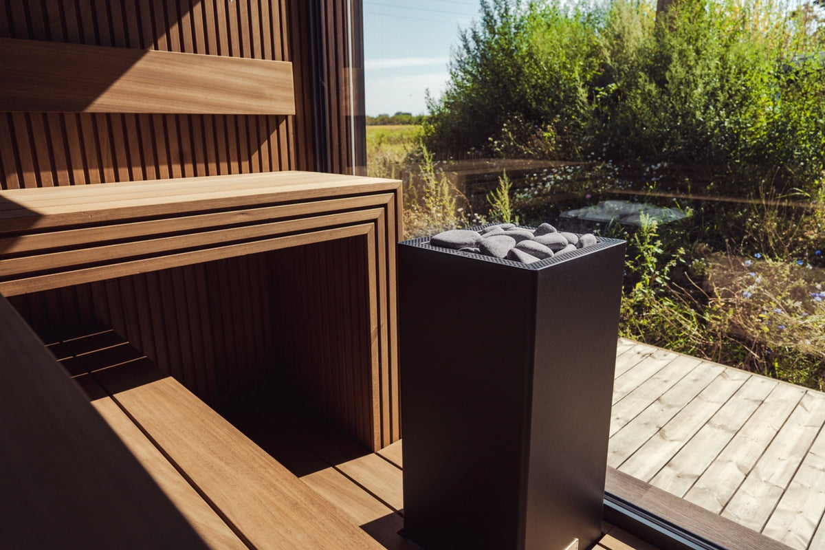 Sauna bench and heater beside a glass wall overlooking greenery