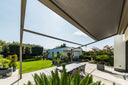 Wall-mounted Renson Lapure retractable fabric roof over a private patio