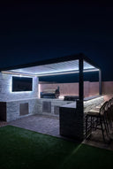 Outdoor kitchen under a lit pergola at night
