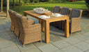 Teak dining table with woven wicker armchairs on a stone patio