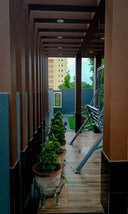 Narrow balcony garden with potted plants and a hanging swing chair