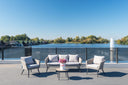 Outdoor sofa set on a lakeside rooftop terrace with a fountain view
