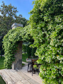 Jasmine covered stone pergola over a timber terrace with a cafe table